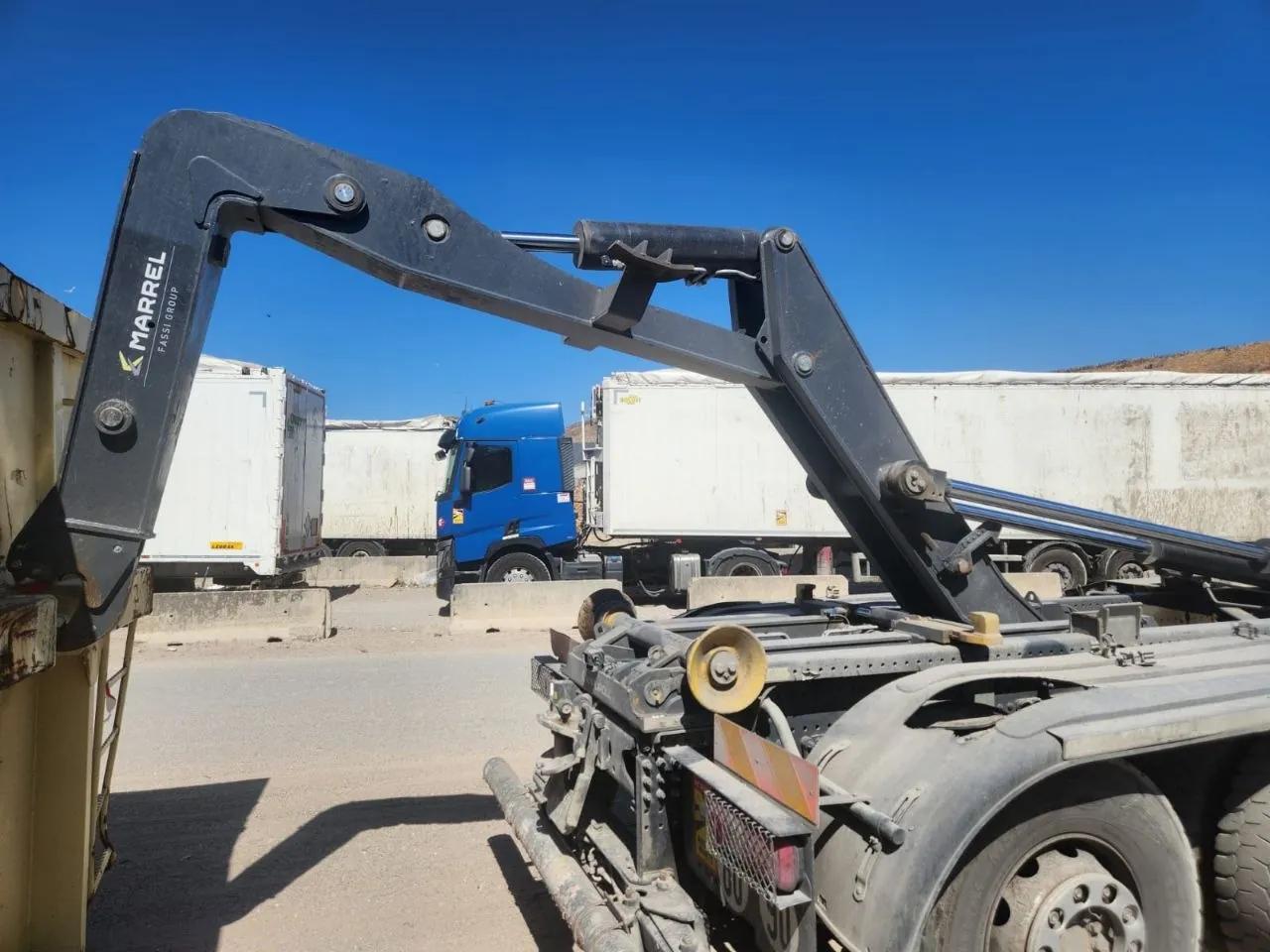 Bras de grue replié, camions à l'arrière-plan